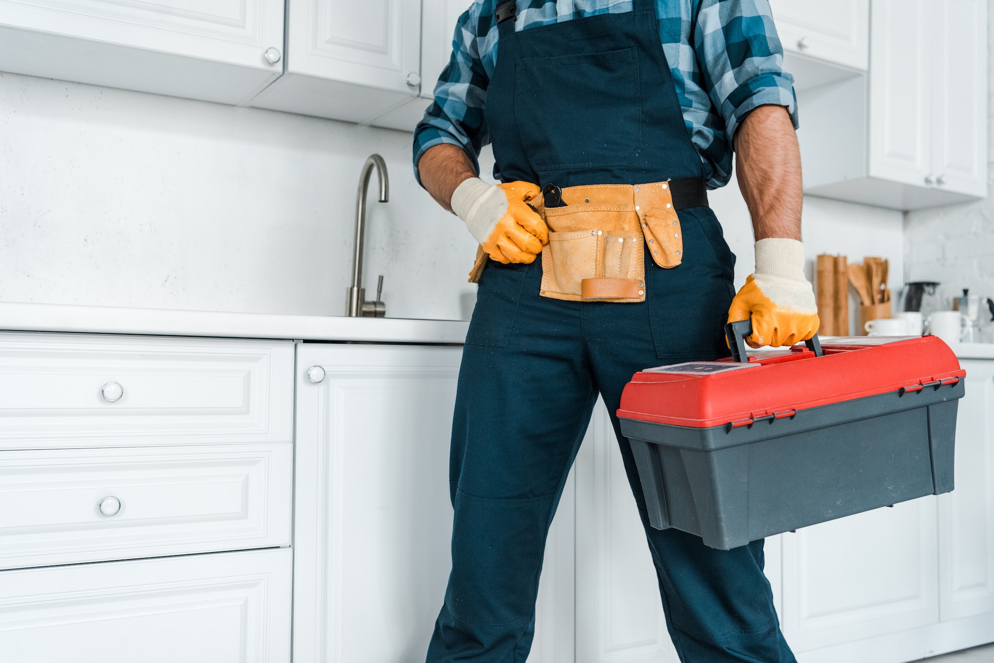 cropped view of handyman in uniform standing and holding toolbox